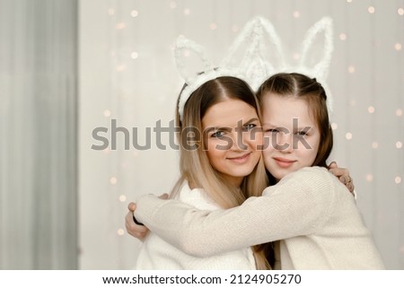 Mother and daughter. A cute blonde girl and her baby are hugging in white headbands with bunny ears. Easter Bunnies. portraits. High quality photo. copy space 