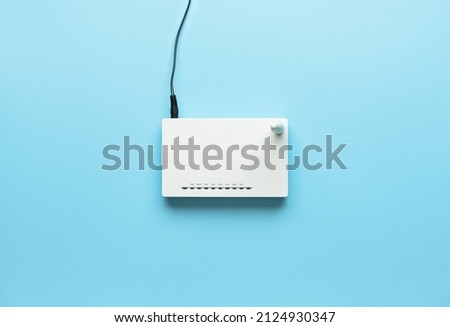 Wi-Fi router with antenna and network cable on color background