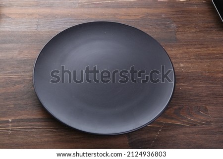 Elegant black table setting: plate, napkin and silverware over dark background. Flat lay. Top view