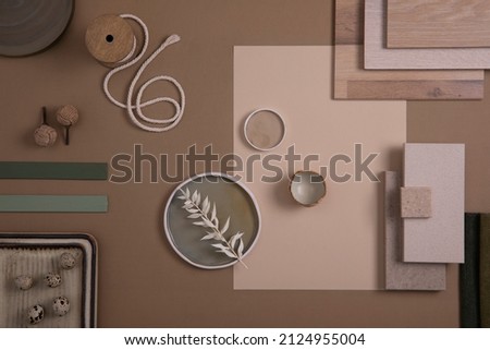 Creative flat lay composition of interior designer moodboard with textile and paint samples, panels and tiles. Beige, brown and green color palette. Copy space. Template. 