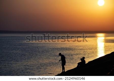 Beautiful summer sunset on the sea. Silhouette of people on the shore. Sea landscape.