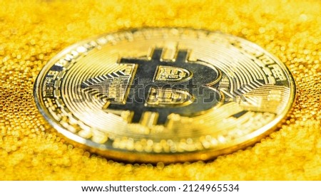 Golden bitcoin on yellow gold placer surface. Crypto currency. Bitcoin mining concept