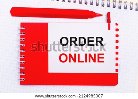 On a white notepad, a red pen, a red notepad and a white sheet of paper with the text ORDER ONLINE