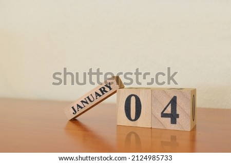 January 4, Date design with calendar cube on wooden table and white background.