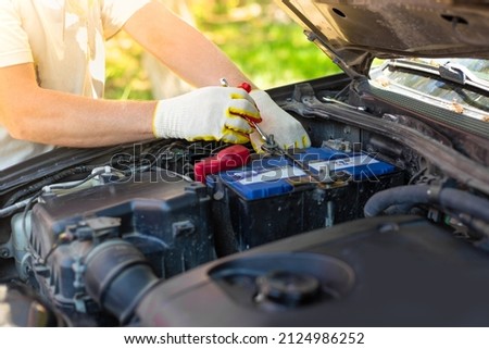 A man unscrews a car battery mount. Battery repair and replacement. Royalty-Free Stock Photo #2124986252