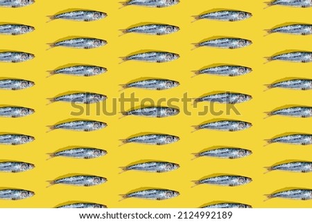 A mosaic of (Engraulis encrasicolus) Fresh silver-colored anchovies on a yellow background. Fish rich in vitamin B with an exquisite flavor. wallpaper, top view