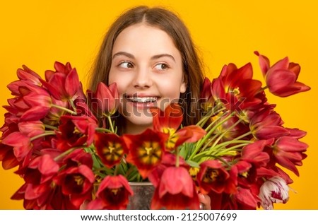 happy girl hold spring tulip flowers on yellow background