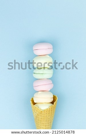 Wafer horn and marshmallow looks like macaroons on a blue pastel background, top view, flat lay, minimalist trend, concept of sweet dessert.