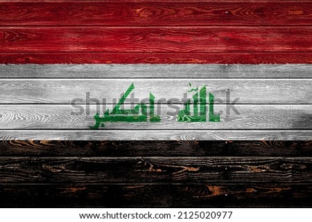 The national flag of Irak is painted on a camp of even boards nailed with a nail. The symbol of the country.