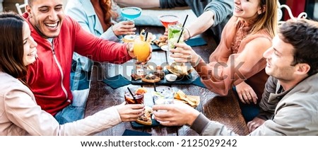 Young people holding multicolored drinks - Trendy fashion friends having fun together toasting cocktails at happy hour - Social gathering life style concept on vivid filter with focus on mid glasses Royalty-Free Stock Photo #2125029242