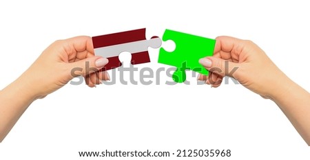 Woman hands are holding part of puzzle game. National mock up on white background. Latvia