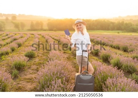 woman with suitcase and passport in lavender field