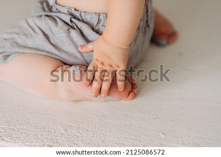 A one-year-old baby is sitting on the floor.