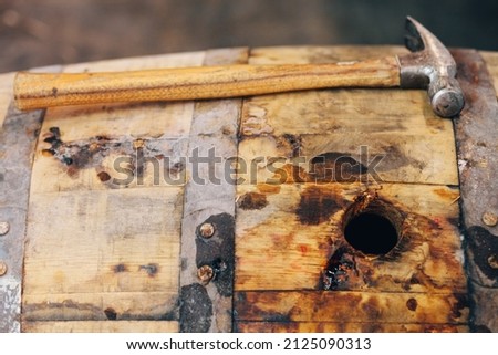 Hammer resting on dusty bourbon whiskey barrel with open bung hole Royalty-Free Stock Photo #2125090313