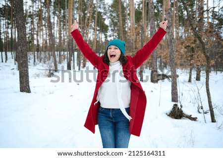 Beautiful happy Caucasian woman having fun, whirling in a snow covered nature, enjoying beautiful cold winter day while walking on a snowy pine forest. Wonderful winter, cool weather. Royalty-Free Stock Photo #2125164311