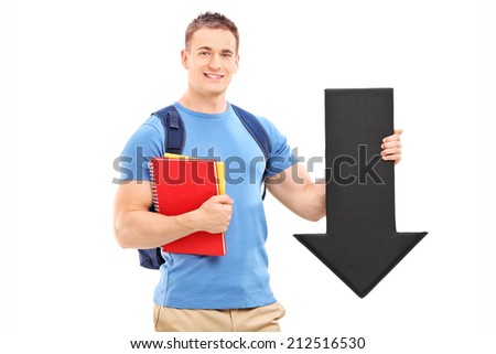 Male student holding a big black arrow pointing down isolated on white background