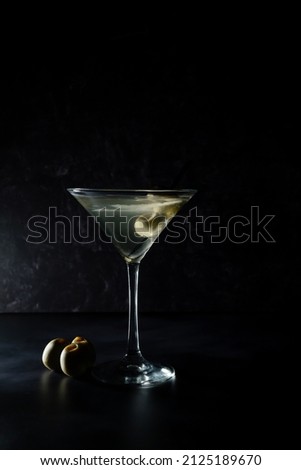 Dirty martini with olives on black background