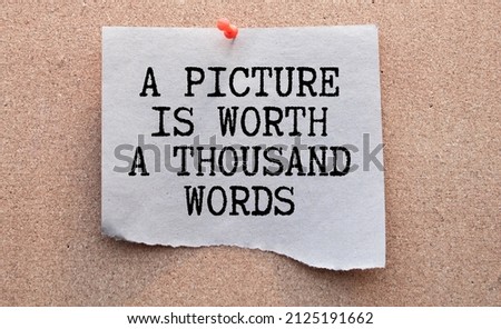 A picture is worth a thousand words Message. Recycled paper note pinned on cork board.