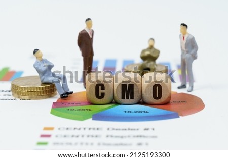 Business and finance concept. On financial reports with diagrams, figures of businessmen and wooden cubes with the inscription - CMO