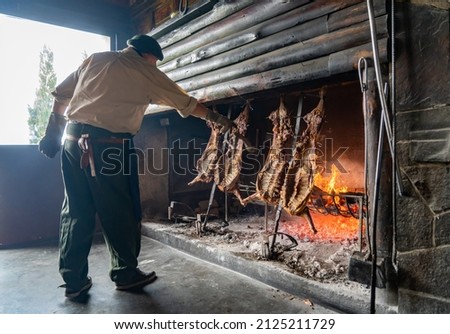 Argentina, Patagonia traditional lamb cooking on an open fireplace. Royalty-Free Stock Photo #2125211729