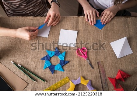 mom and daughter make origami from colored paper on self-isolation