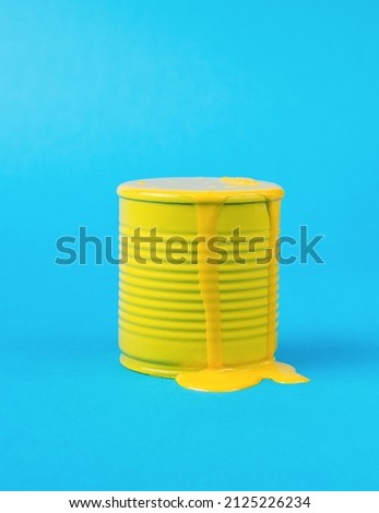 An overflowing jar with leaking yellow paint on a blue background. Trending colors. Minimal concept of interior selection.