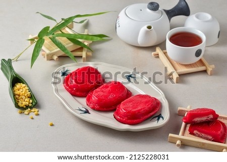 Ang ku kueh or Kue Tok or Kue Ku, as known as Red tortoise cake, is a small round or oval-shaped Chinese pastry with soft, sticky glutinous rice flour skin wrapped. Served on plate with tea Royalty-Free Stock Photo #2125228031