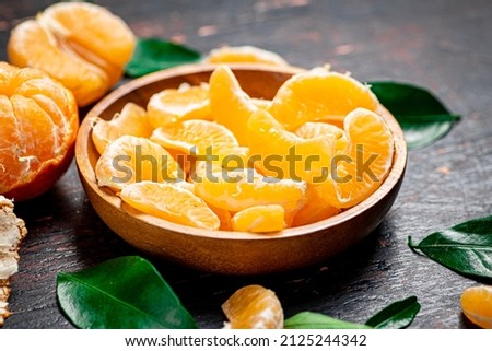 Pieces of fresh tangerines on a plate with leaves. On a rustic dark background. High quality photo