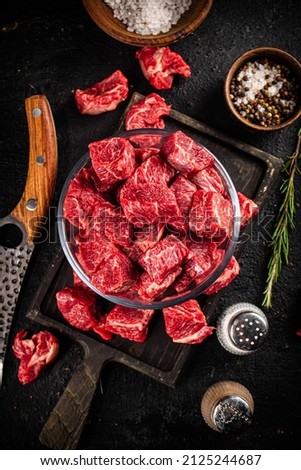 Raw beef tenderloin in a glass bowl with spices. On a black background. High quality photo