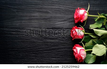 Three red roses lie on a black background