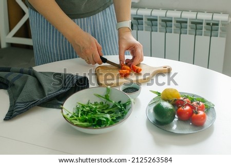 Woman preparing vegetable salad with tomato in the kitchen. Healthy food vegan salad. Mindful eating. Royalty-Free Stock Photo #2125263584