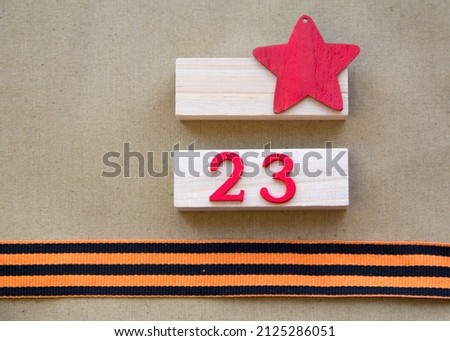 Background of Defender of the Fatherland Day. February 23. A clean notebook, a military cap, a St. George ribbon. Space for text. A red star on a green background. February 23