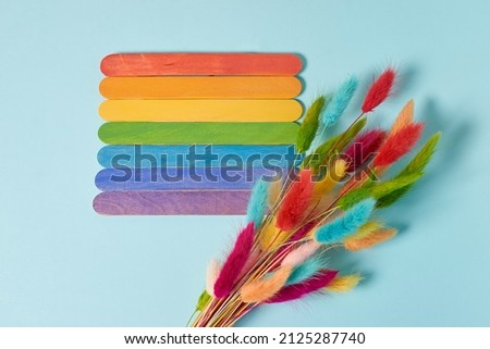 Mock up. Rainbow plaques and a bouquet of colorful dried lagurus flowers on a blue background. Top view, free windows, copy space