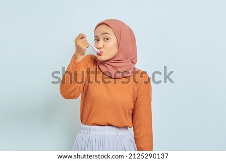 Beautiful young Asian woman in brown sweater licking spoon eating delicious meal dish isolated on white background Royalty-Free Stock Photo #2125290137