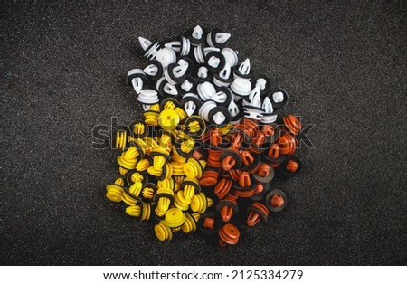 Macro photography of plastic multi-colored clips for a car on a gray background. Car clips, plastic fasteners, multicolored plastic clips on a gray background close-up.Car clips and fasteners. Royalty-Free Stock Photo #2125334279