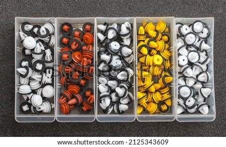 Plastic multi-colored clips for a car in a container box on a gray background. Car clips, plastic fasteners, colorful plastic clips close-up in a box. Car clips and fasteners close-up. Royalty-Free Stock Photo #2125343609
