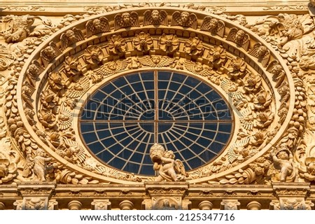 Lecce, Puglia, Italy. August 2021. The church of Santa Croce is the finest example of Lecce baroque. Detail of the facade illuminated by the warm light of the evening. The central rose window.