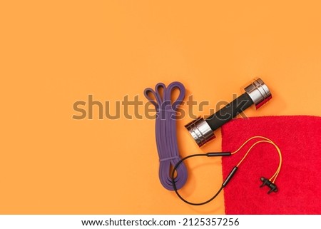 Set of sports accessories massage roller, resistance band, headphones on a yellow background
