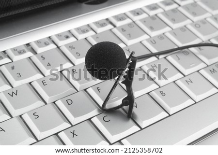 Black lapel microphone on laptop computer. Interview, blogging and internet streaming concept.