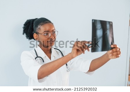 X-ray with picture of bones. Young african american woman is against white background.