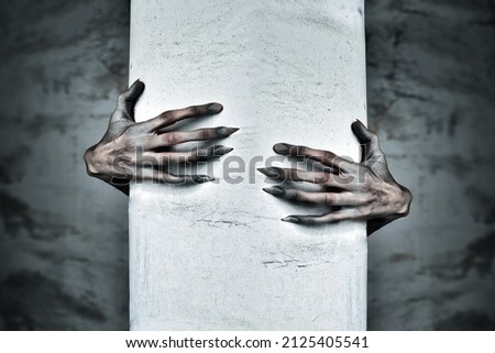 A Pair of Scary Hands Reach Out from Behind a COlumn Royalty-Free Stock Photo #2125405541