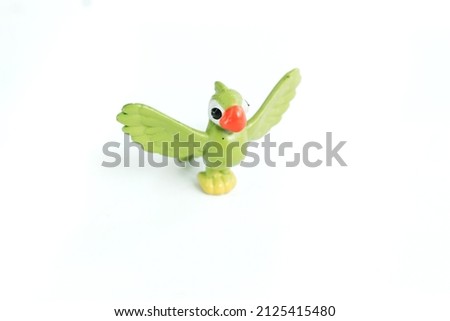 Green bird toy standing made of plastic on an isolated white background, can be used as a medium to introduce flying animals to children