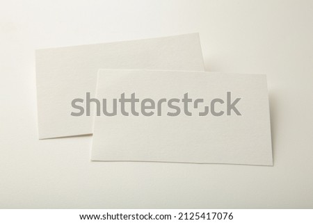 Blank white business cards on white paper background. Mockup for branding identity. Template for graphic designers portfolios.