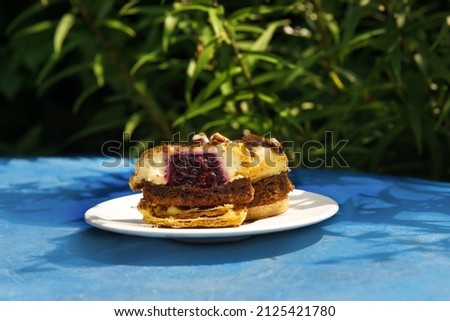 Muffins of small sizes with raspberries on a blue background in bright sunlight. Summer pastries. Confectionery blog, banner in a cafe and a restaurant. Menu of confectionery.Favorable, sweet proposal