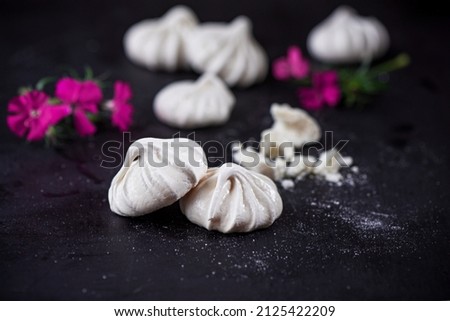 White merengues on a black wooden background, close up, macro photography