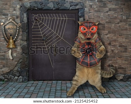 A beige cat is wearing a spider costume near a door of his house. Spidercat.