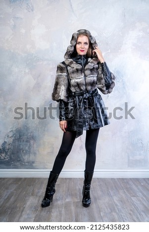 Fashionable clothes showing in a photo studio. Collection winter and spring. Stylish fur coat made of natural fur, mink, chinchilla, scribe, leather. Vertical banner for a magazine or sign, clothes