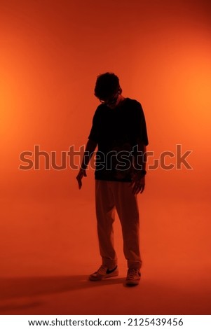 A man is dancing. The silhouette of a dancer. Orange background. Desktop wallpapers. A man in motion.