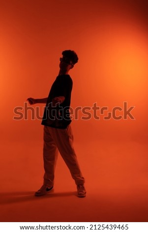 A man is dancing. The silhouette of a dancer. Orange background. Desktop wallpapers. A man in motion.