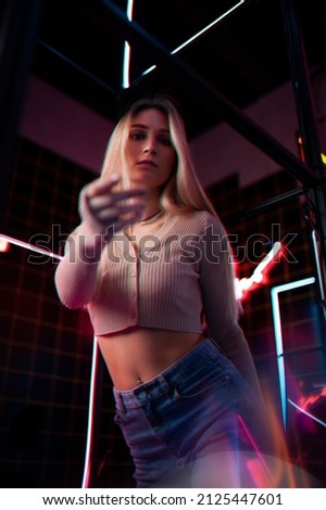 A young blonde girl in a room with neon. Neon light and portrait. Modern design. Bright light. Multicolored photo.